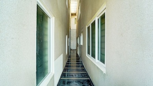 A narrow corridor with a tiled floor leading to a staircase. - Collection O Charing Cross Ooty (Ooty)