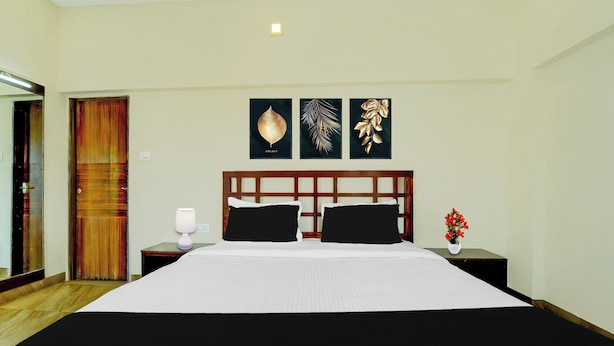 A hotel room with a large bed, two nightstands, a bedside lamp, and three framed leaf artworks on the wall. - Collection O Charing Cross Ooty (Ooty)