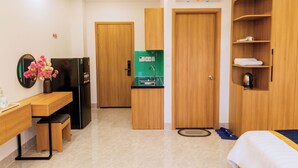 A hotel room with a bed, a desk, a refrigerator, a small kitchenette, and a wardrobe.