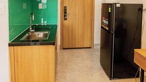 A compact kitchen with a sink, a refrigerator, and wooden cabinets.
