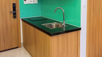 Una cocina compacta con armarios de madera, una encimera negra y un lavamanos de acero inoxidable.