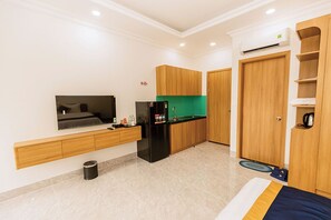 A compact hotel room with a kitchenette, a bed, a TV, and a wardrobe. - Nova Hotel Nhon Trach (Nhon Trach)