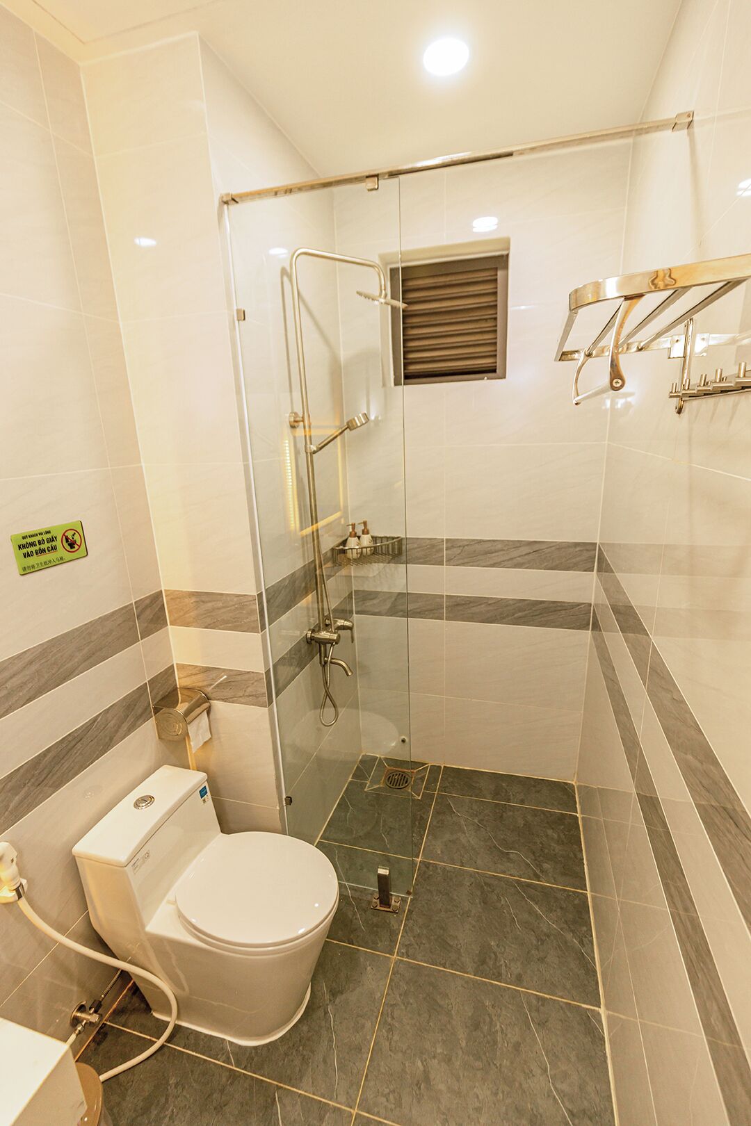 A modern bathroom with a glass-enclosed shower, a toilet, and a sink.
