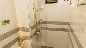 A modern bathroom with a glass-enclosed shower, a toilet, and a sink.