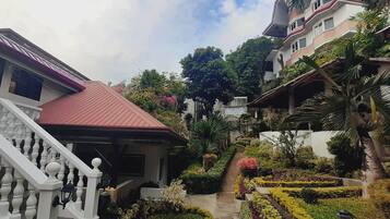 A residential area with a staircase leading to a red-roofed building, surrounded by lush greenery and a well-maintained garden.