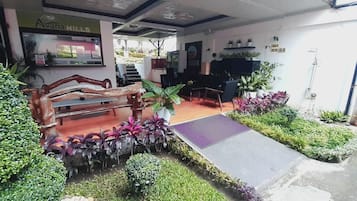 Vestíbulo de hotel con recepción, área de descanso y plantas en macetas.