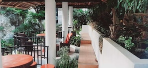 A covered outdoor seating area with tables and chairs, surrounded by lush greenery and a stone wall. - Avana Hills Boracay Prime - Horizon 2 (Boracay Island)