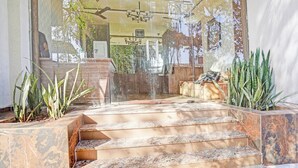 Eine Treppe aus Marmor führt zu einer Holzterrasse mit Gartenmöbeln.