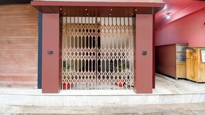 Entrada de un edificio moderno con una verja metálica, un persiano cerrado a la izquierda y un armario de madera a la derecha.