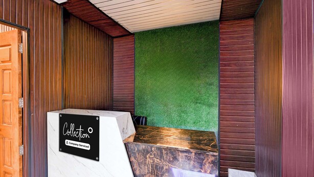 Un área de recepción con puerta de madera, mostrador de recepción y pared verde.