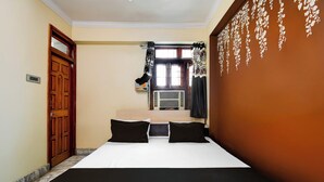 Habitación de hotel con cama, ventana con cortinas, aire acondicionado montado en la pared y una puerta.