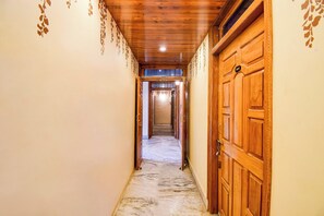 A hallway with wooden doors and a marble floor. - Super Collection O Transport Nagar Metro (Patna)