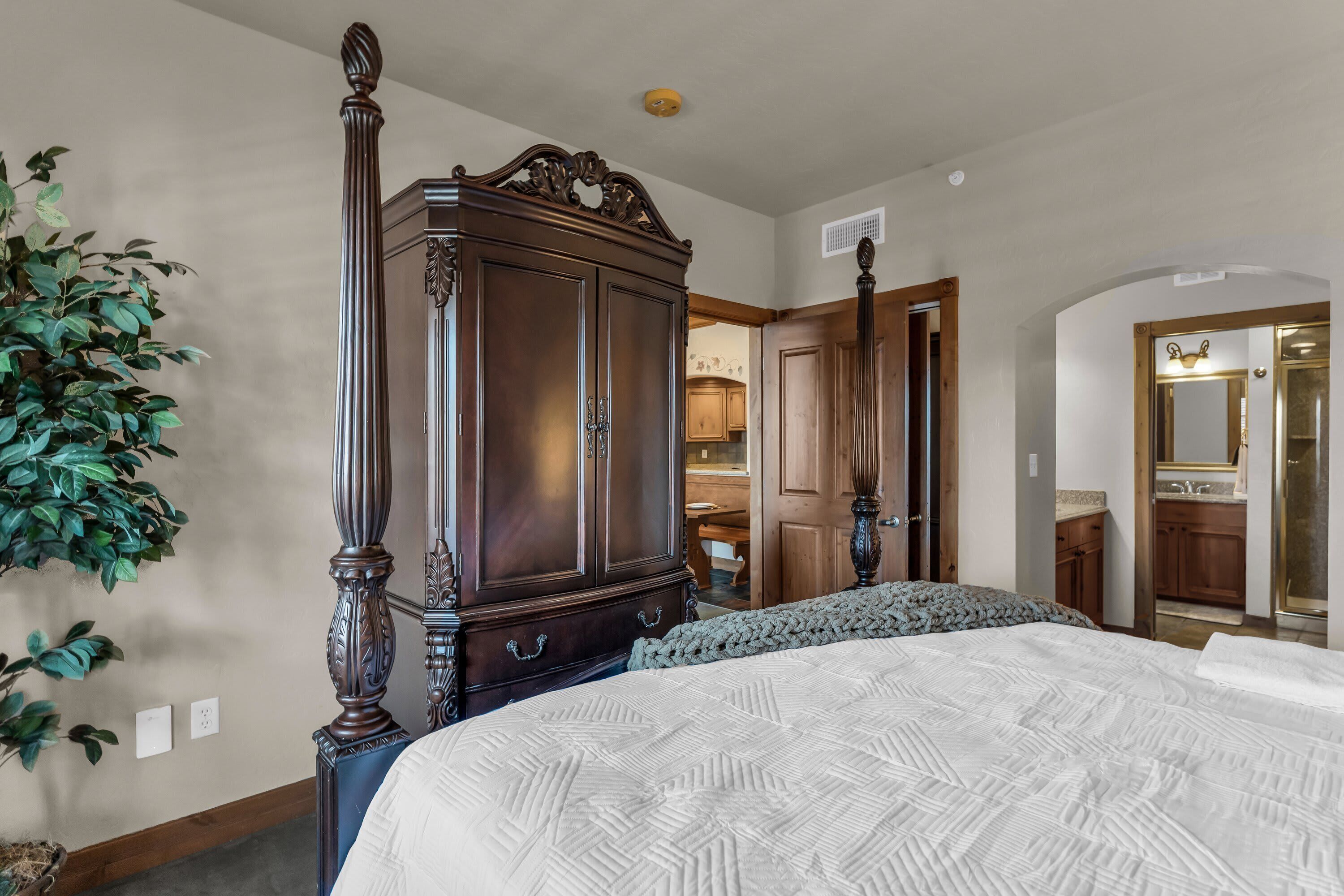 Quarto com cama de dossel, um guarda-roupa espaçoso e um vaso com planta.