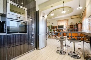 A modern kitchen with stainless steel appliances, a bar area with stools, and a dining space with chairs. - Eretria Panorama Seaview Retreat with Balcony (malakonta)