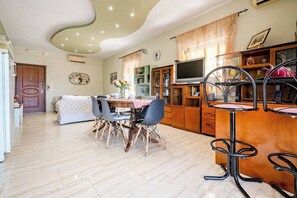 A modern living room with a dining area, a TV, and a bar area with stools. - Eretria Panorama Seaview Retreat with Balcony (malakonta)