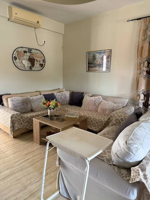 A living room with a sofa, a coffee table, a wall clock, and a painting. - Eretria Panorama Seaview Retreat with Balcony (malakonta)