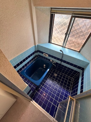 A small bathroom with a blue bathtub, a window, and a tiled floor. - Spacious 4-Bedroom, 2-Bathroom House Near Kyoto: Nintendo Museum & Torii Gates (Uji)