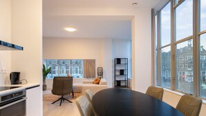 A modern living room with a dining table, a sofa, and a large window with a city view. - Modern 2 Bedroom Apartment in Rotterdam City Center With Free Parking (Rotterdam)