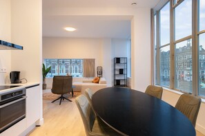A modern living room with a dining table, a sofa, and a large window with a city view. - Modern 2 Bedroom Apartment in Rotterdam City Center With Free Parking (Rotterdam)