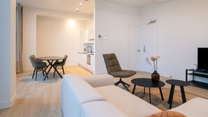 A modern living room with a sofa, a dining table with chairs, a coffee table, a TV, and a small side table with a vase. - Modern 2 Bedroom Apartment in Rotterdam City Center With Free Parking (Rotterdam)