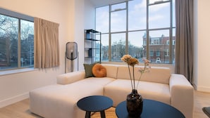 A modern living room with a sofa, a small round table, and a vase with flowers. - Modern 2 Bedroom Apartment in Rotterdam City Center With Free Parking (Rotterdam)