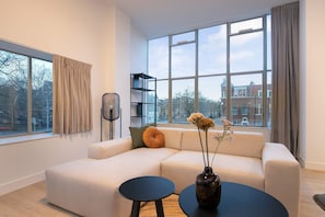 A modern living room with a sofa, a small round table, and a vase with flowers. - Modern 2 Bedroom Apartment in Rotterdam City Center With Free Parking (Rotterdam)