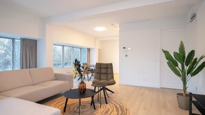 Ein modernes Wohnzimmer mit einer Couch, einem Sessel, einem Couchtisch und einem großen Fenster.