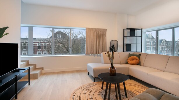 Ein modernes Wohnzimmer mit einer Couch, einem Couchtisch, einem Fernseher und einem Bücherregal.