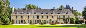 A large, multi-story building with a symmetrical facade, multiple windows, and a well-maintained lawn. - Ch Teau de la Villedubois (Mordelles)
