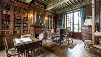 A library with wooden bookshelves, a fireplace, and a large window.