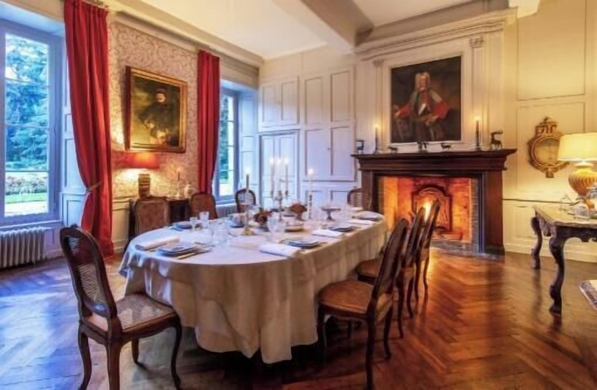 A formal dining room with a long table set for a meal, flanked by chairs, a fireplace, and a painting.