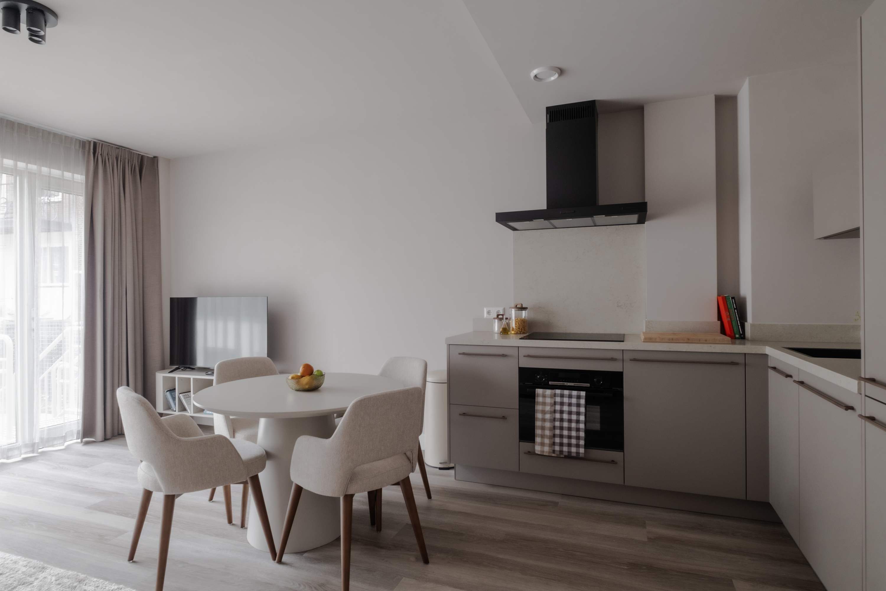 Eine moderne Küche mit Essbereich, ausgestattet mit einem runden Tisch, Stühlen und einem eingebauten Backofen.