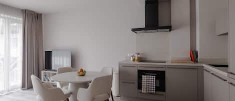 A modern kitchen with a dining area, featuring a round table, chairs, and a built-in oven.