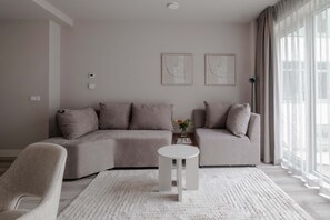 A modern living room with a sectional sofa, a round coffee table, and a small side table with a vase. - Modern Apt in City Centre 2 With Free Parking (Rotterdam)