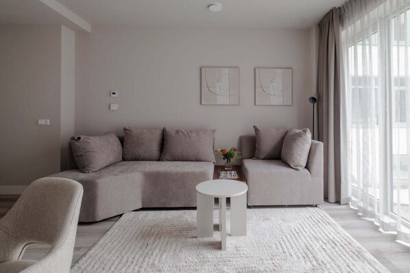 A modern living room with a sectional sofa, a round coffee table, and a small side table with a vase.