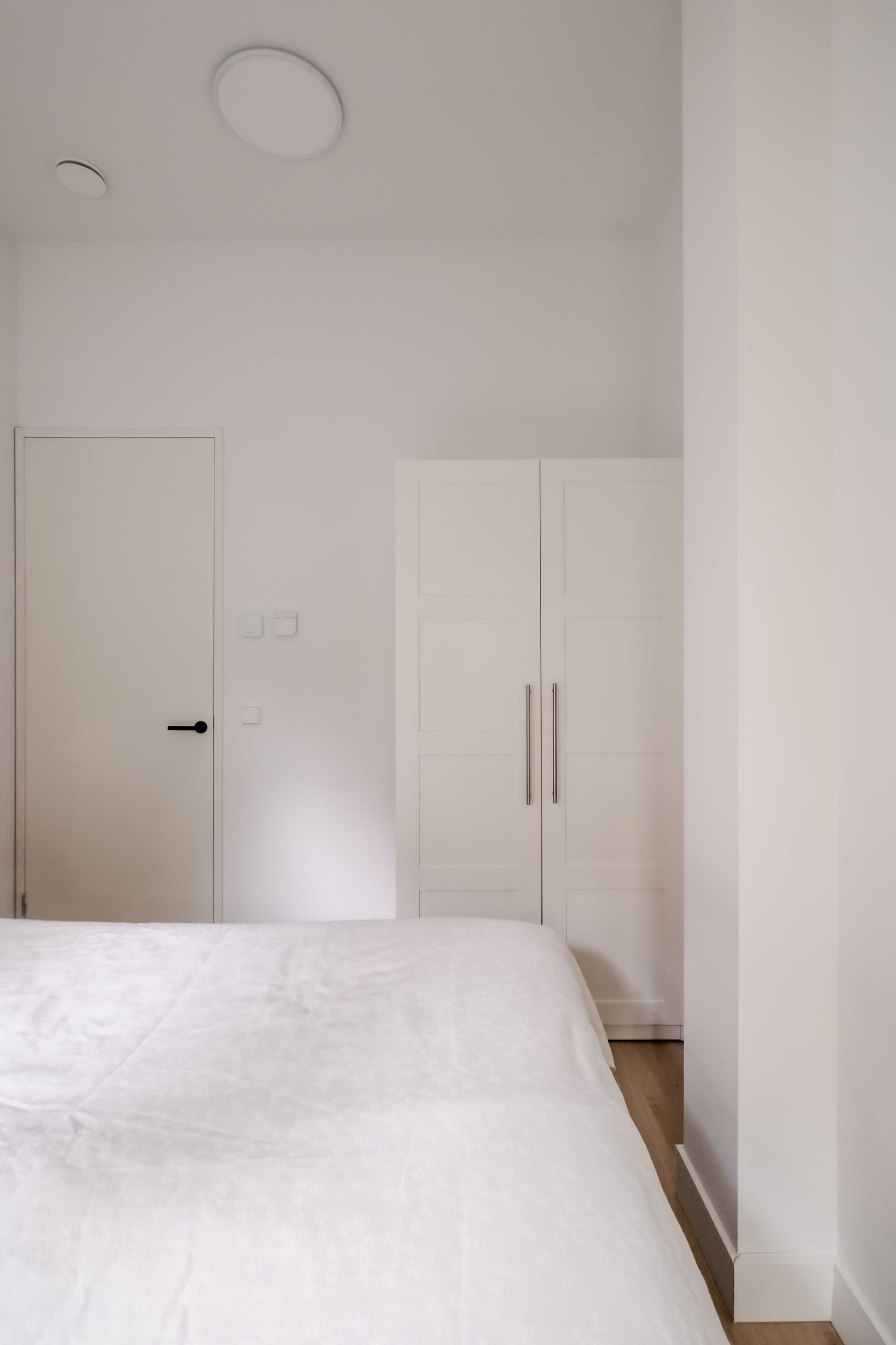 A bedroom with a bed, a wardrobe, and a door.
