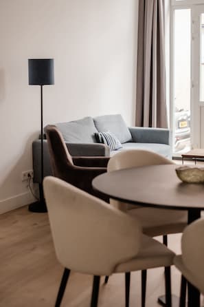 A modern living room with a sofa, a dining table, and a floor lamp. - Spacious 2BR in Heart of Schiedam (Schiedam)