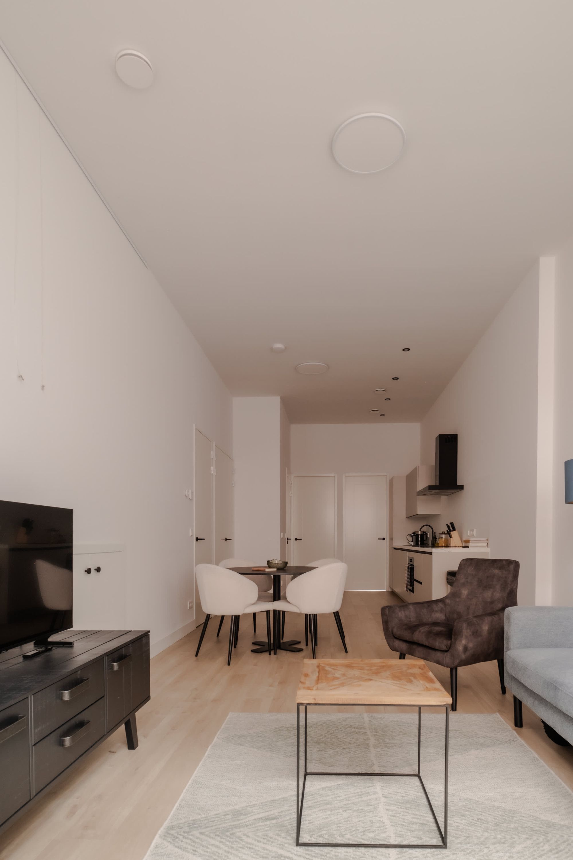 A modern living room with a flat-screen TV, a coffee table, and a sofa.