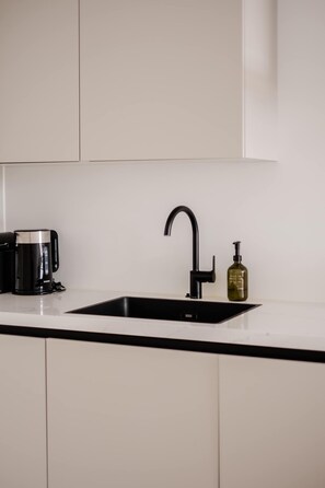 A kitchen with a black faucet, a coffee maker, and a bottle of olive oil on the counter. - Spacious 2BR in Heart of Schiedam (Schiedam)