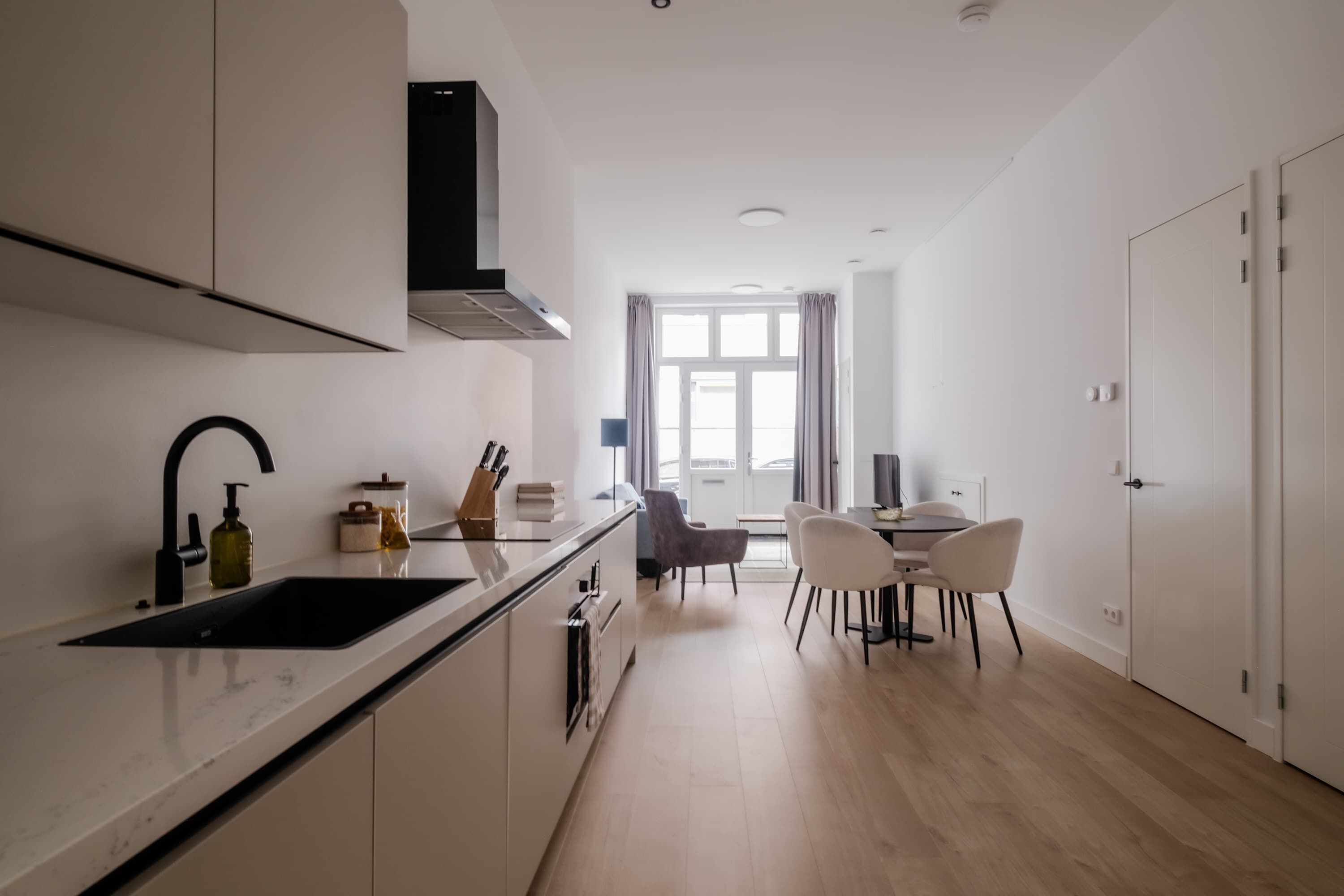 Une cuisine moderne équipée d’un four encastré, d’un évier et d’un coin repas avec une table et des chaises.