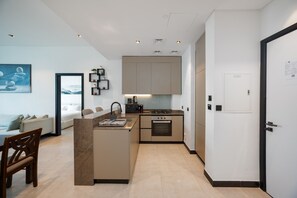 A modern kitchen with a central island, built-in appliances, and a dining area with a sofa and chairs. - Modern 2BR Retreat | Near Downtown Dubai (Dubai)