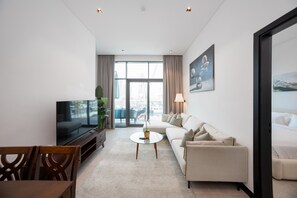 Ein modernes Wohnzimmer mit Flachbildfernseher, einer Couch, einem Couchtisch und einem Essbereich mit Stühlen.