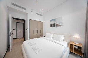 A hotel room with a bed, a nightstand, a lamp, a wardrobe, and a door. - Modern 2BR Retreat | Near Downtown Dubai (Dubai)