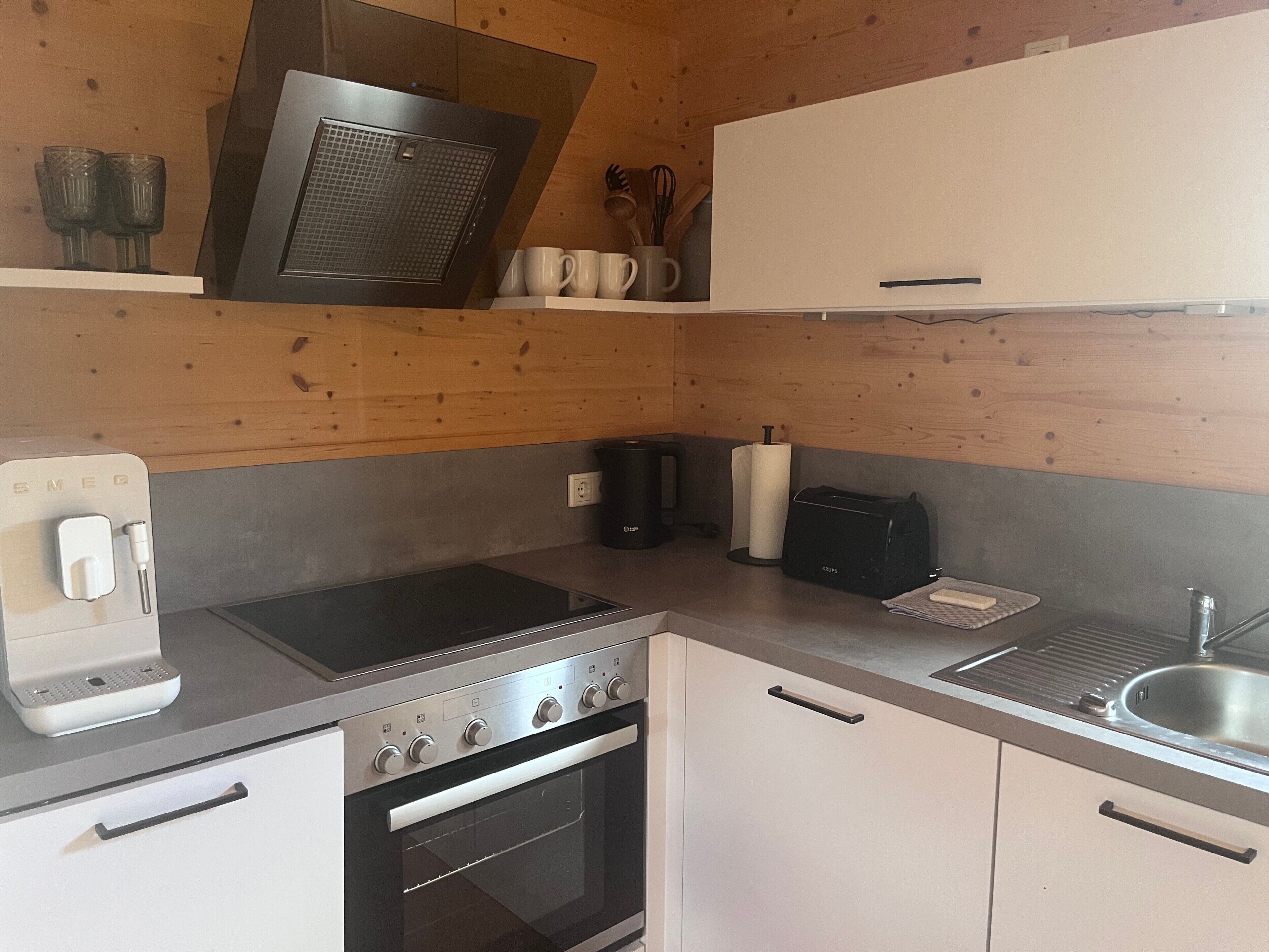 Una cocina compacta con horno empotrado, cocina, cafetera y tostadora.