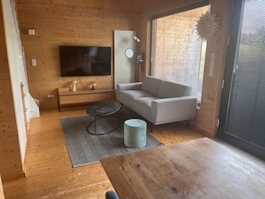 A modern living room with a flat-screen TV, a sofa, a coffee table, and a small round table.