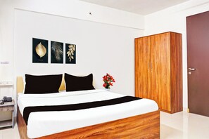 A bedroom with a bed, a wardrobe, a nightstand, and a wall-mounted artwork. - Super Collection O Baner (Pune)