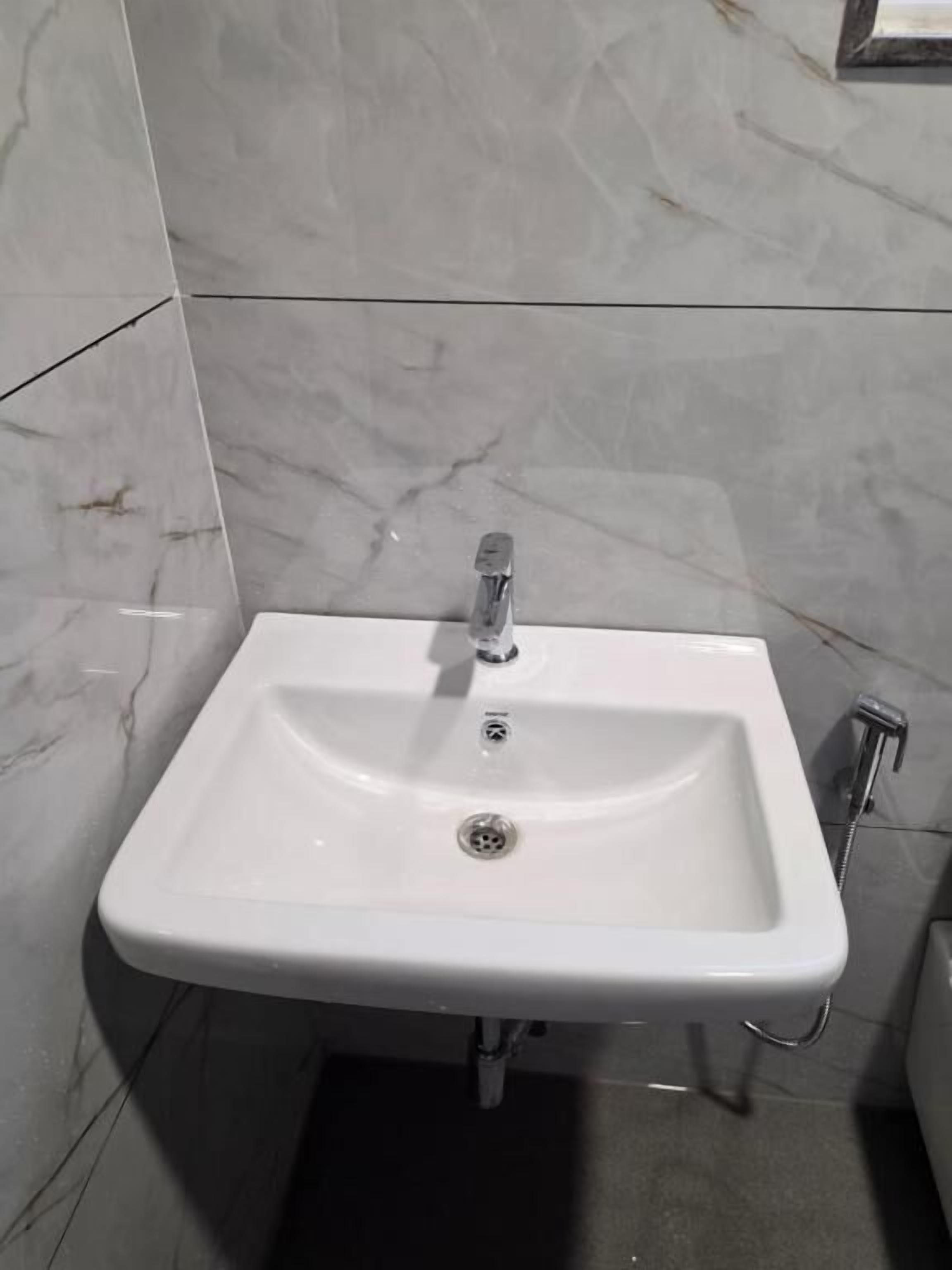 Un lavamanos de diseño moderno, con un solo grifo y un mando de cromo.