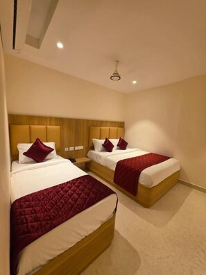 A hotel room with two beds, each with a wooden headboard and red bedding.