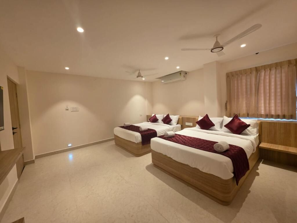 Habitación de hotel con dos camas, ventilador de techo y ventana con cortinas.