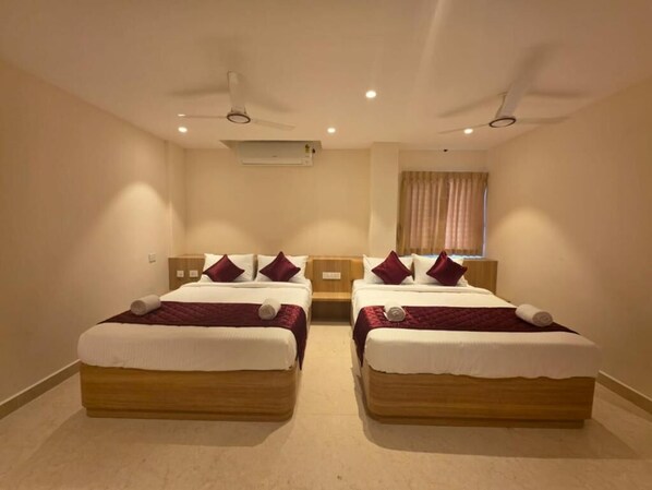 A hotel room with two beds, a ceiling fan, an air conditioning unit, and a window with curtains.